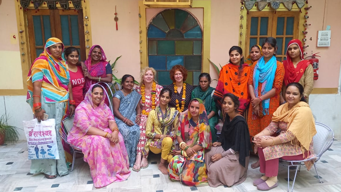 Group of women in colorful traditional attire posing for a photo in a decorated indoor setting.