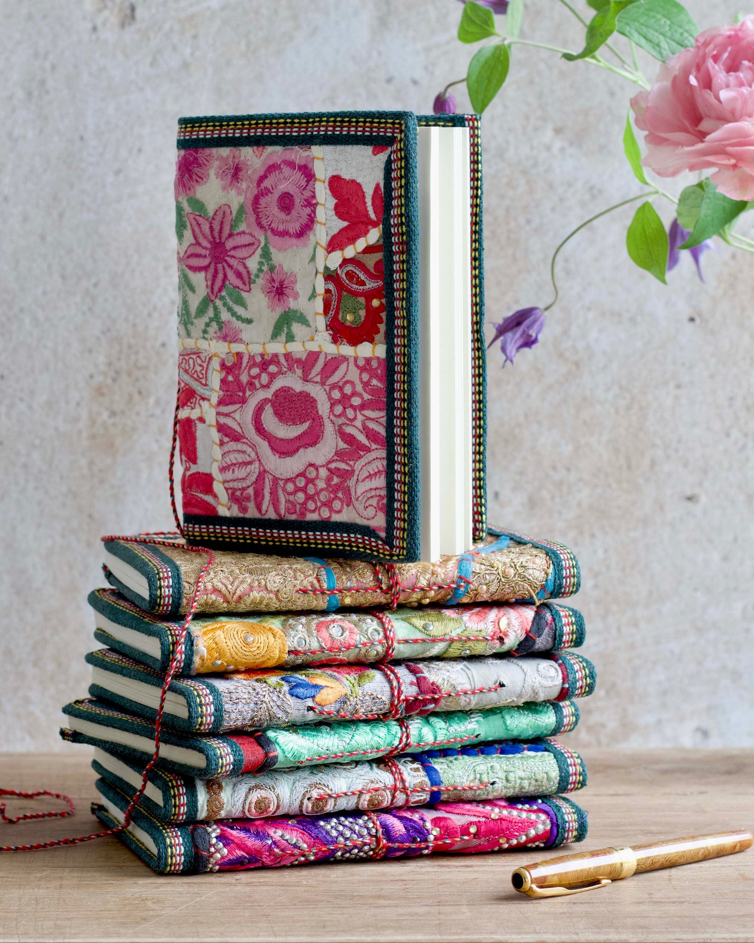 Stack of colorful fabric books with floral patterns on a wooden surface.