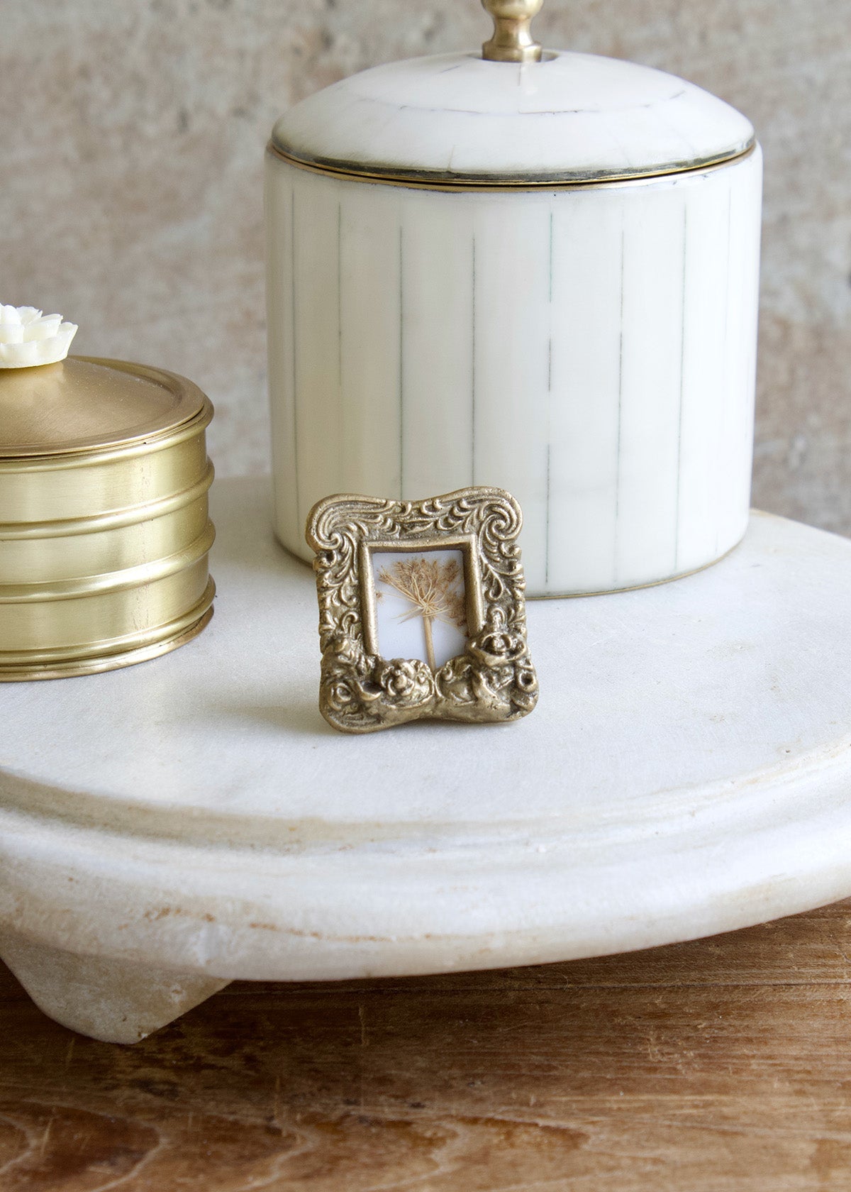 Decorative white container with gold accents on a marble surface