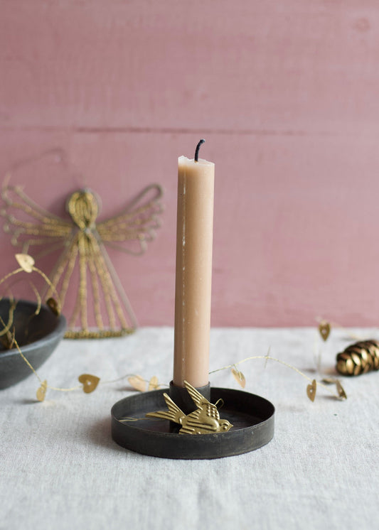 Black iron round candle holder with a beige taper candle on a linen table.