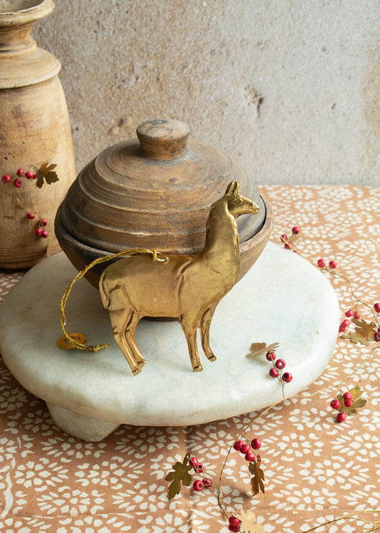Brass llama ornament with gold string on marble tray and rustic background