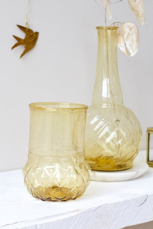 Amber yellow glass vase with a sculpted diamond-patterned base, styled on a white shelf.