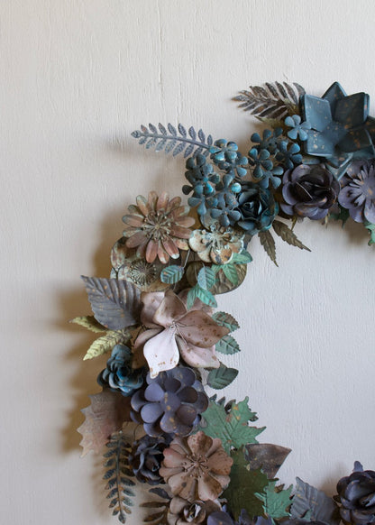 Handgemaakte metalen bloemenkrans in zachte blauw- en groentinten