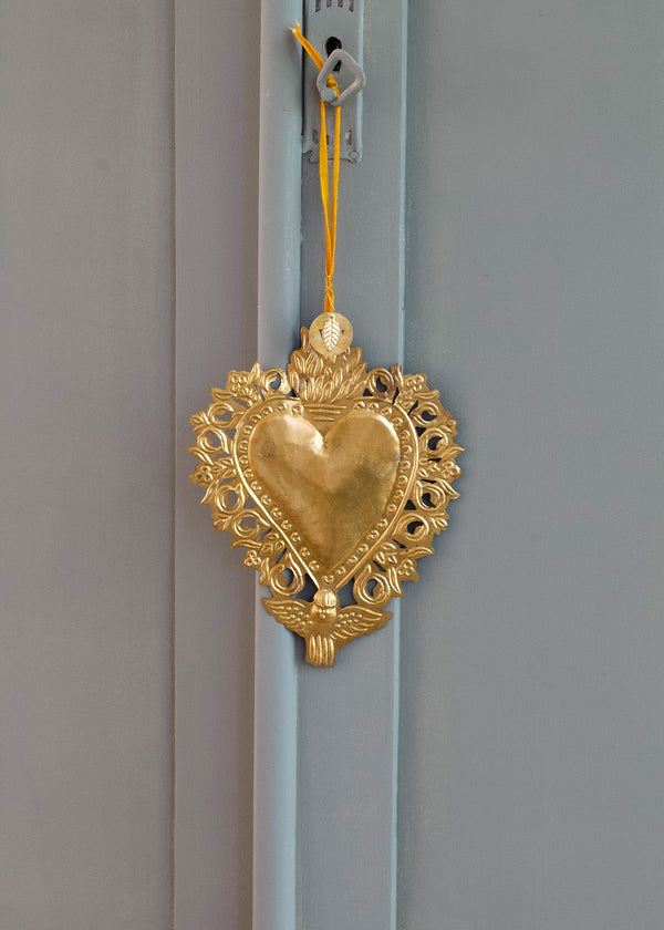 Decorative gold heart-shaped ornament hanging on a light blue door.