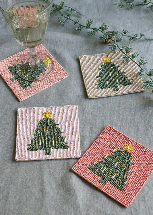 Set of four beaded coasters with Christmas tree design on a gray surface.