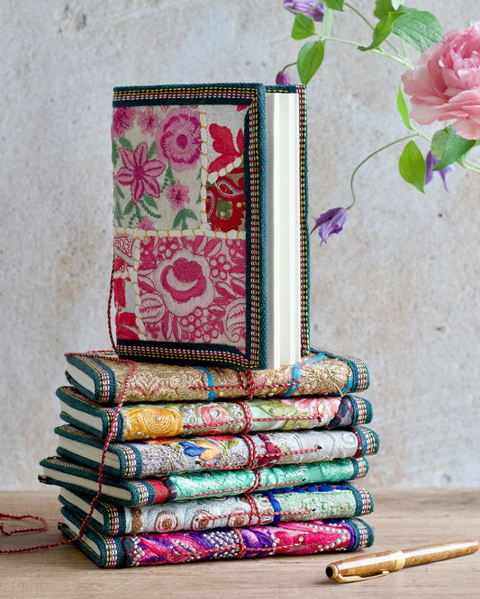 Stack of colorful fabric books with floral patterns on a wooden surface.