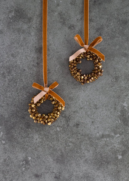 Two decorative wreath ornaments with ribbons on a gray surface