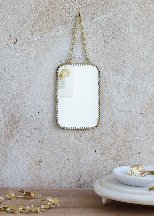 Medium rectangular mirror with rounded corners, brass frame and double chain hanger, styled on a stone wall with golden accessories and a marble tray.