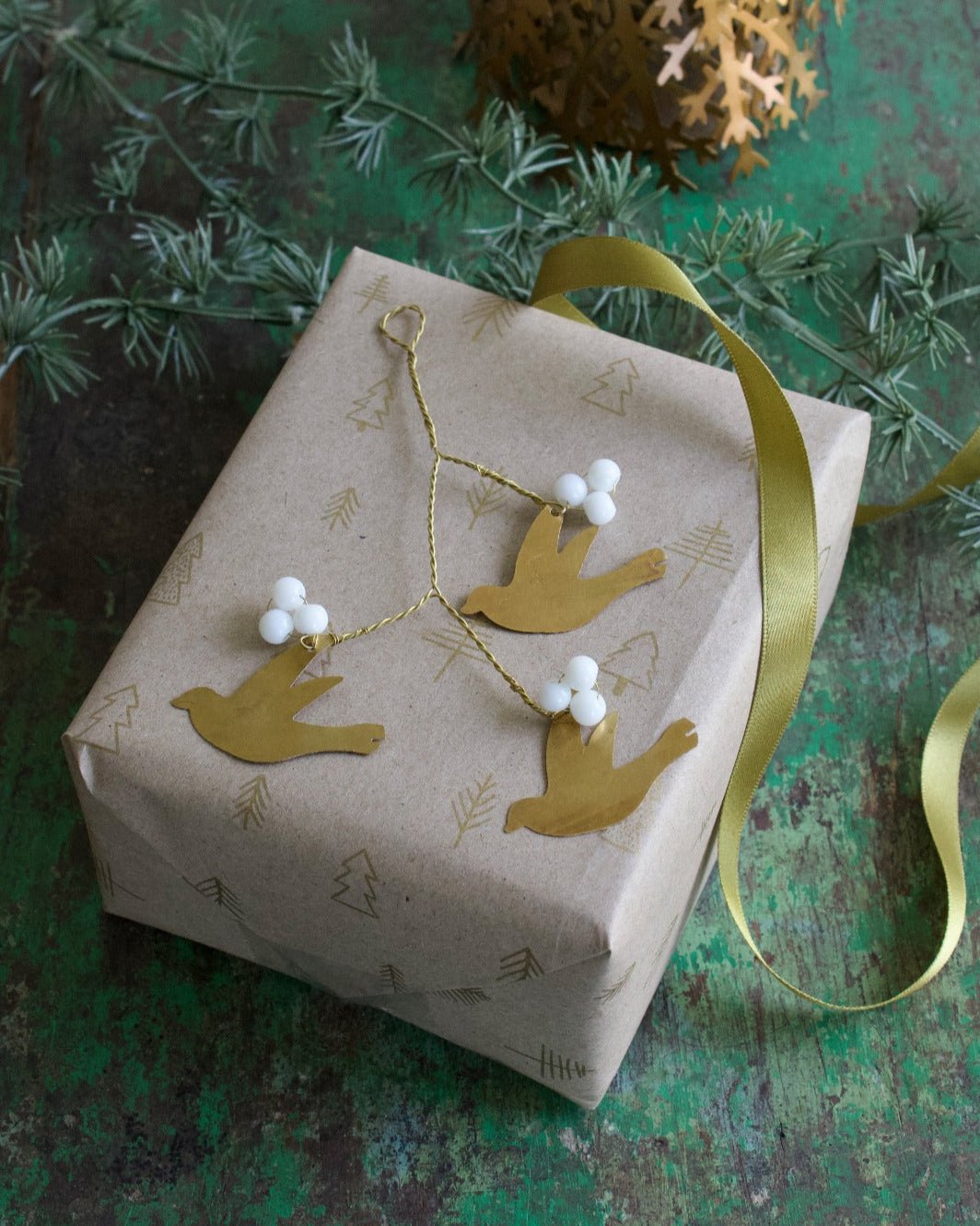 Gift box with decorative birds and white berries on a textured green surface