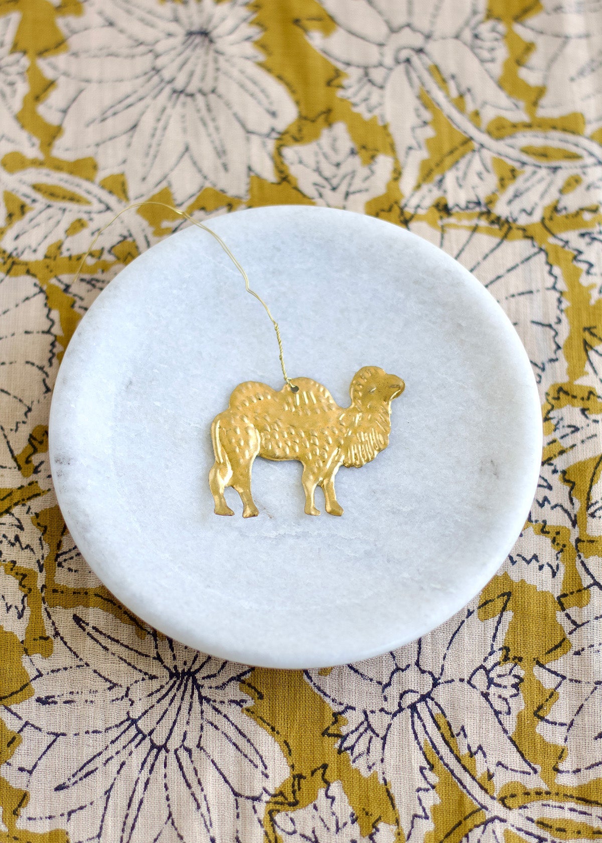 Marble coaster with gold camel design on a floral fabric background