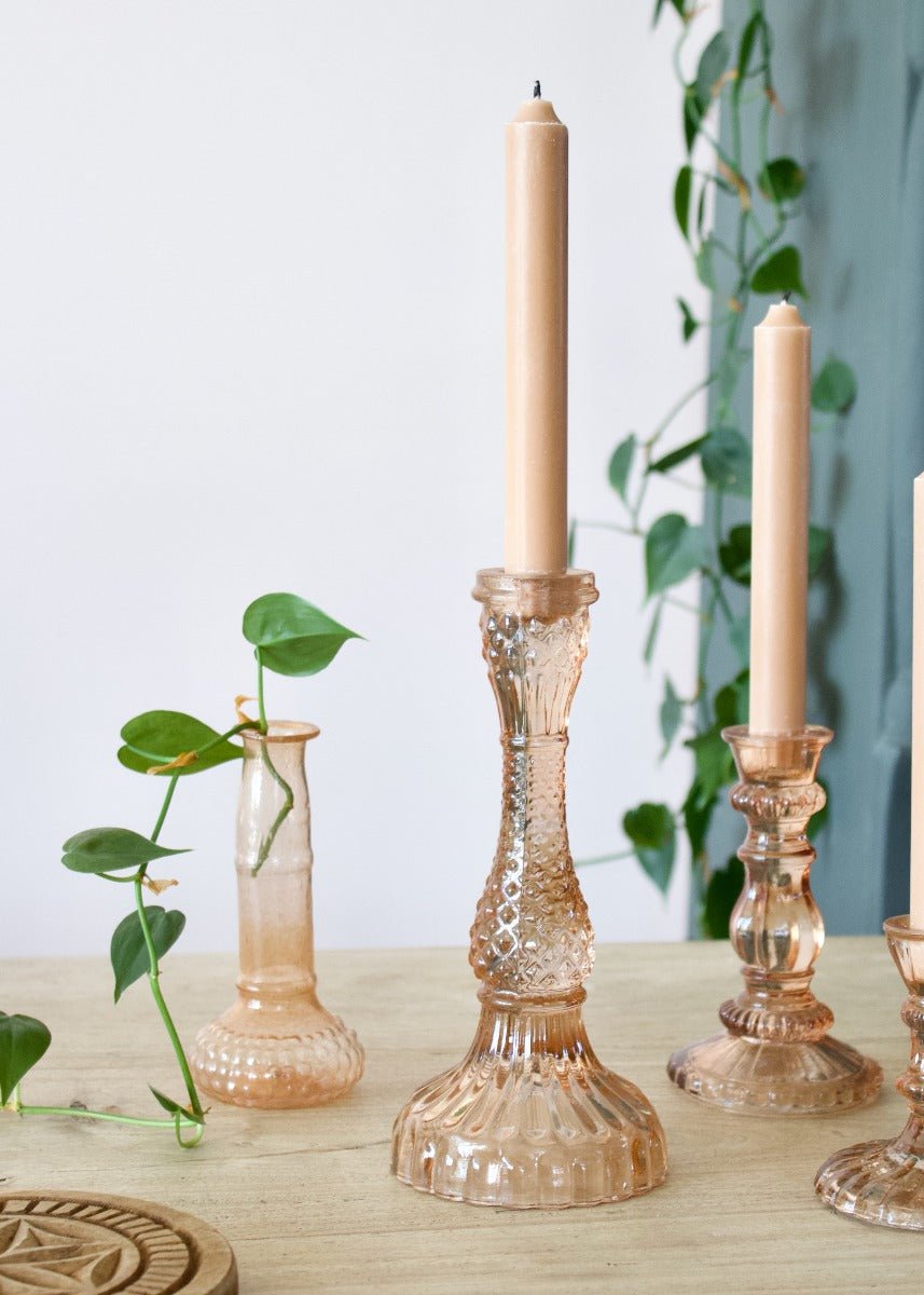 Decorative glass candlestick holders with candles on a wooden surface.
