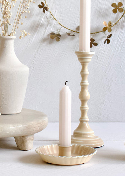 Decorative setting with candles, a vase, and a shell-shaped candle holder on a light background.