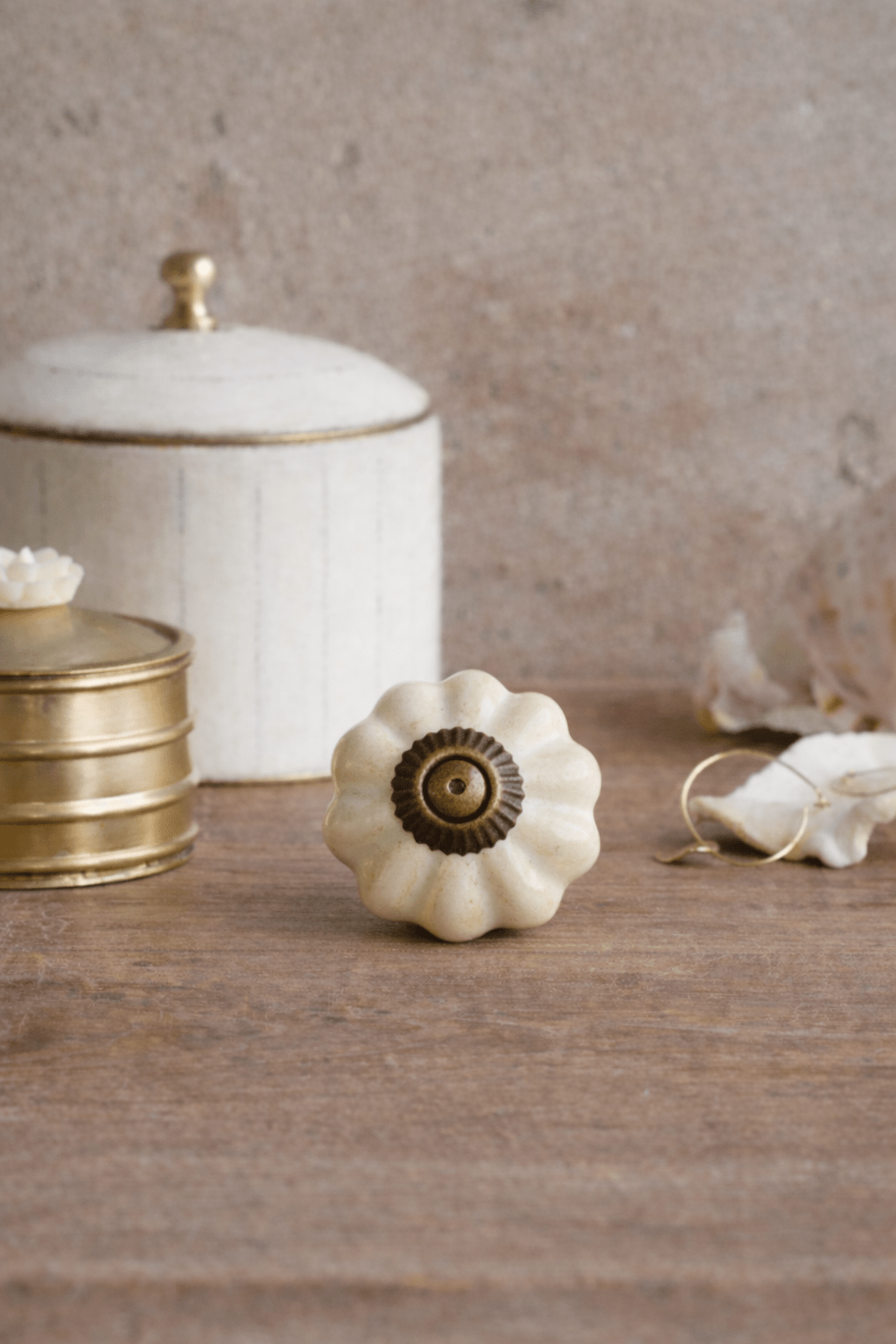 Decorative white knob with gold center on a wooden surface with a neutral background