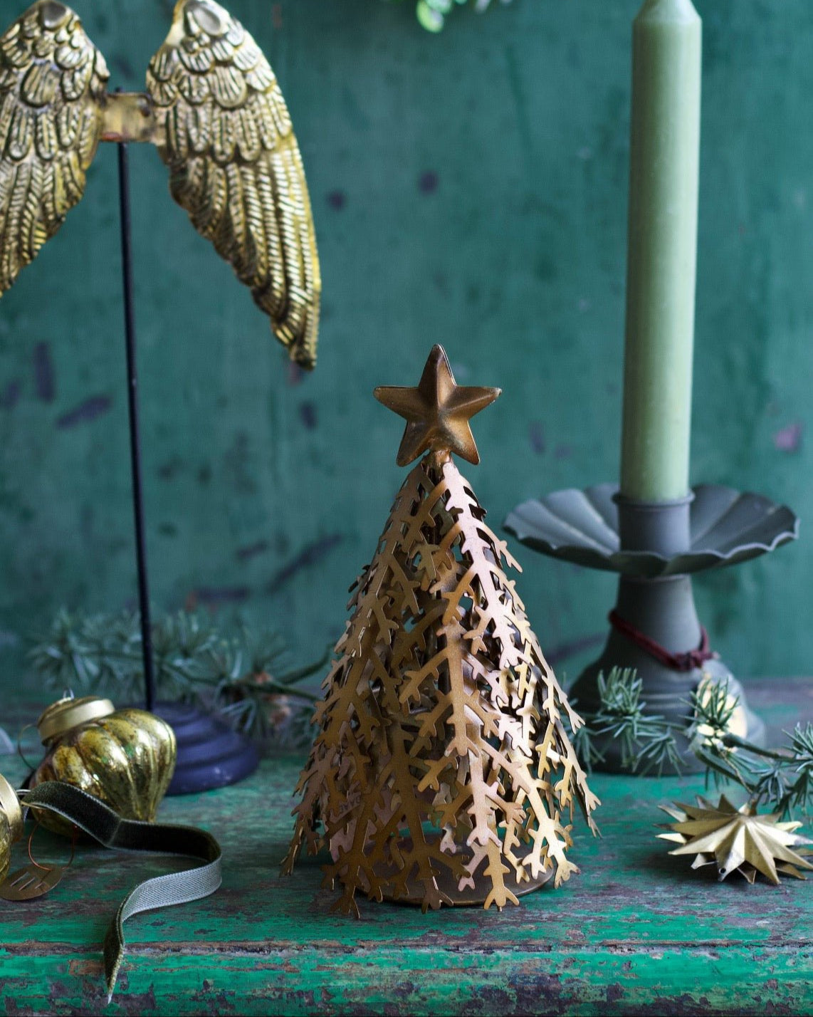 Decorative Christmas tree with star on a green surface with candle and angel wings.