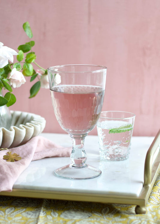 Two glasses of pink water on a marble surface with a pink background