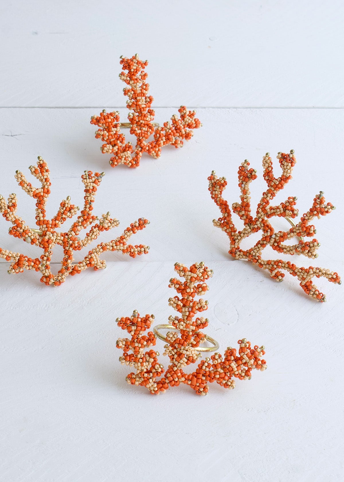 Set of four orange coral-shaped earrings on a white background