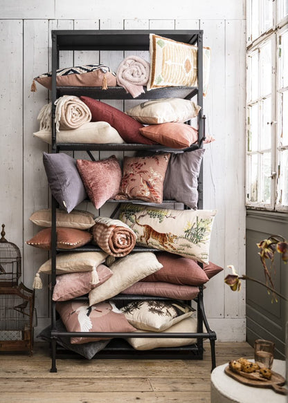 Black metal shelf with pillows and blankets against a white wall.