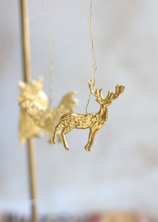 Gold deer ornament hanging against a blurred background