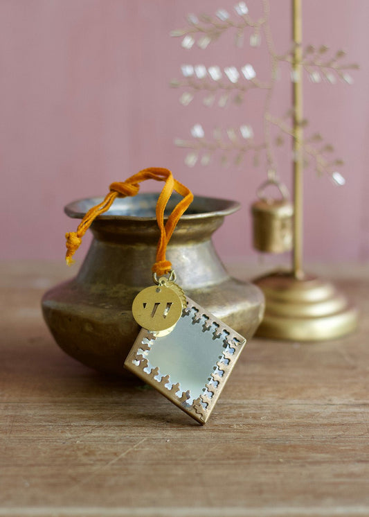 Diamond-shaped ex voto mirror ornament with golden frame and orange ribbon, styled with brass accents.