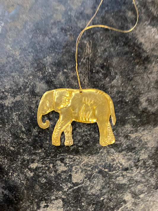 Handmade brass elephant hanger with fine detailing, shown against a rustic green background.