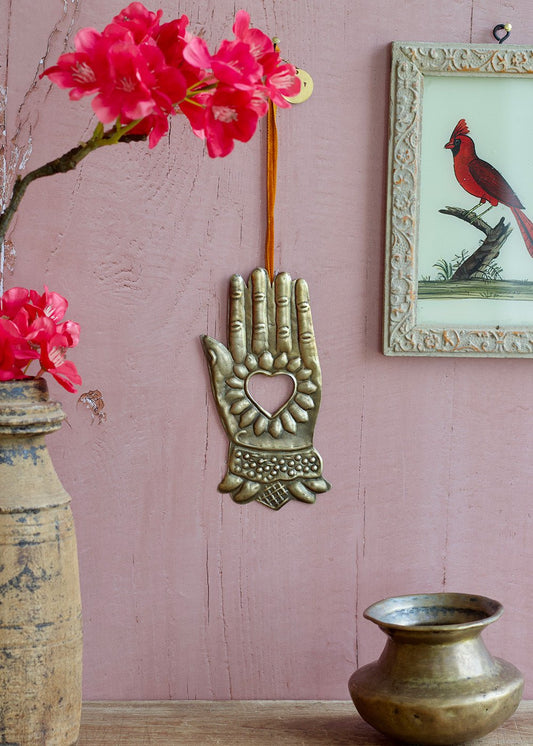 Decorative wall hanging with pink flowers and a framed picture of a cardinal on a pink wall.