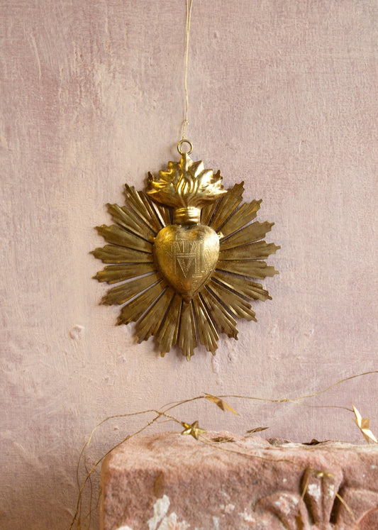 Golden ex-voto sacred heart ornament with engraved details, radiant beams and flame crown.