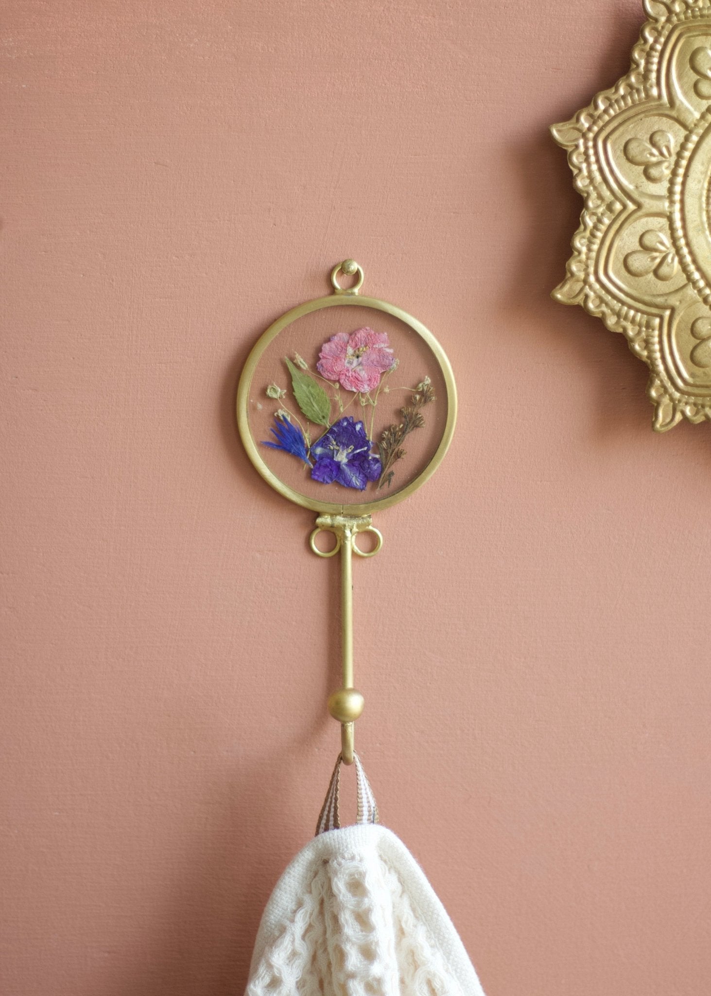 Decorative wall hook with floral design on a pink wall