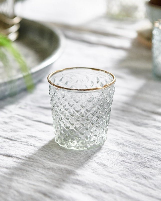 Clear textured glass with gold rim on a light surface