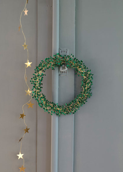 Green wreath with gold stars hanging on a gray door