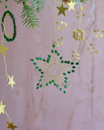 Decorative hanging stars and green circular ornaments on a pink background