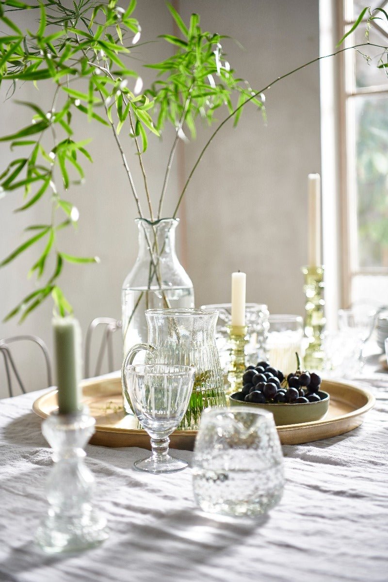 Transparent wineglass decorated with vases & leaves on a white surface