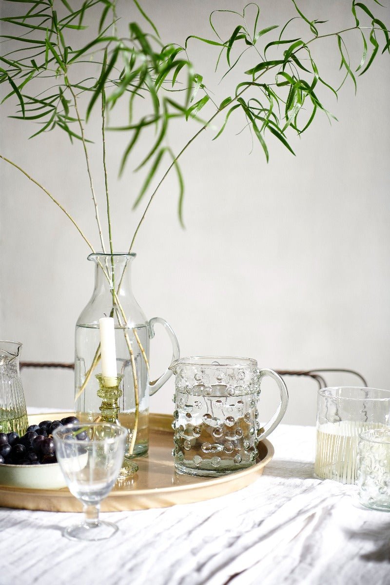 Transparent wineglass decorated with vases & leaves on a white surface
