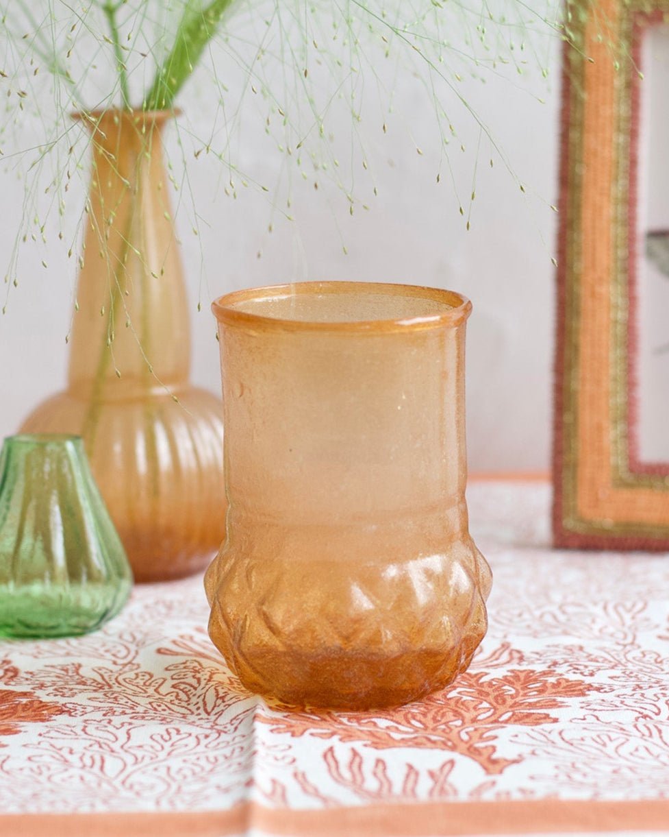 Three glass vases on a table with a framed picture in the background