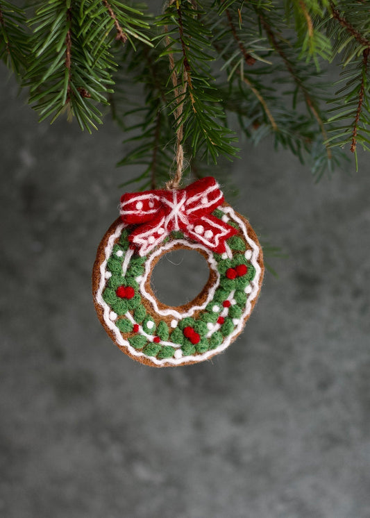 Decorative Christmas ornament shaped like a wreath with a red bow hanging on a tree.