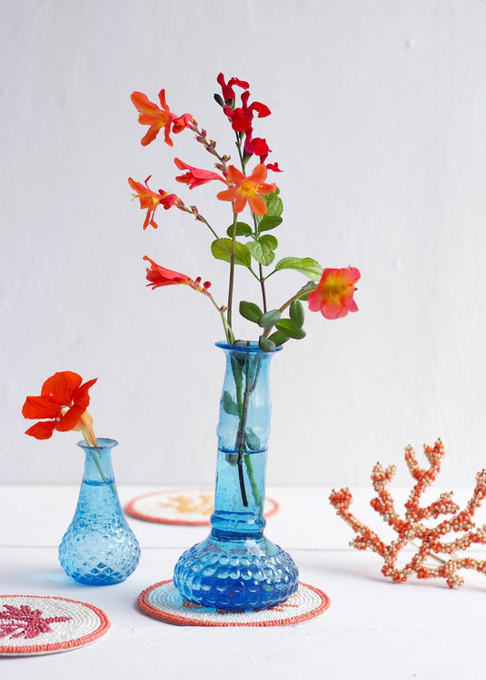 Blue textured vase with red flowers on a white surface