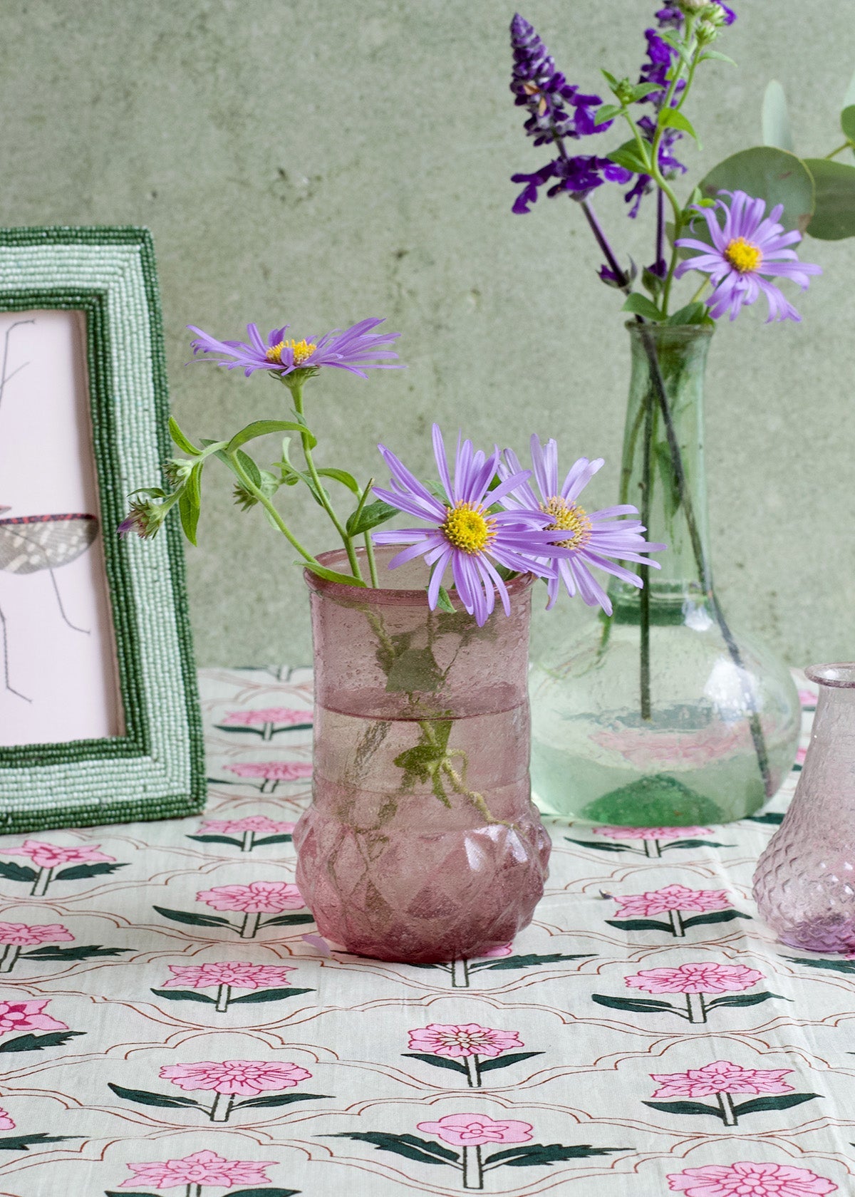 Vases with purple flowers on a tablecloth with floral pattern