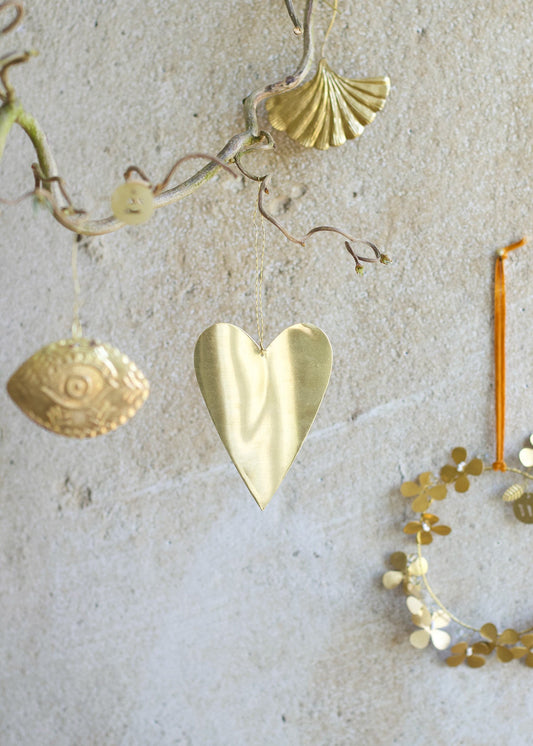 Decorative gold heart ornament hanging on a textured wall