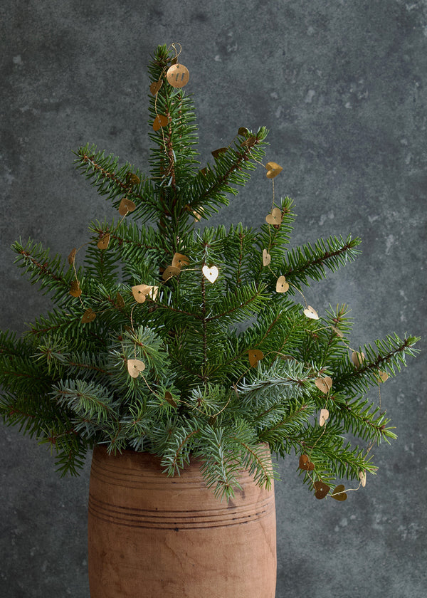 Potted artificial Christmas tree with decorative elements on a dark background