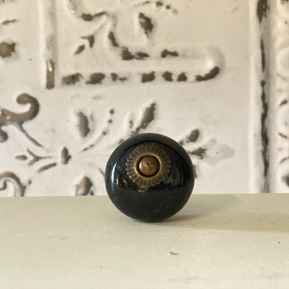 A black round knob with a geometric pattern in the background.