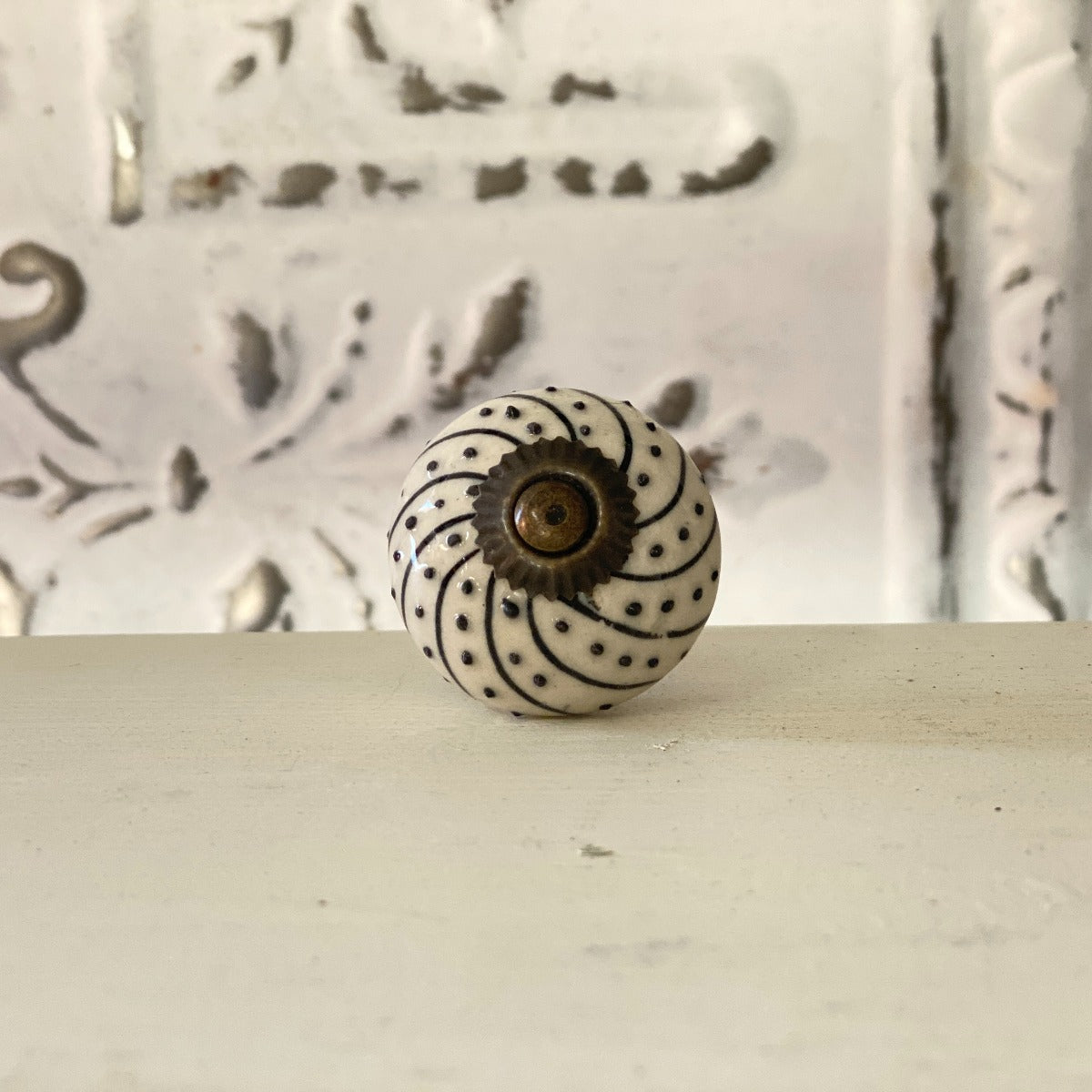 A black and white spiral patterned furniture knob with a visible center fastening mechanism, placed against a textured background.