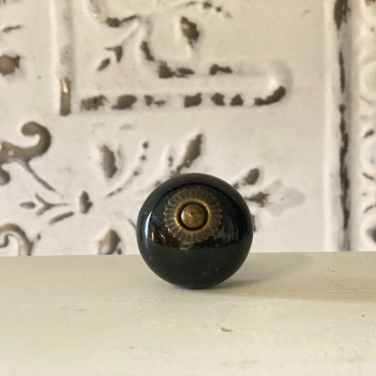 A black round knob with a geometric pattern in the background.