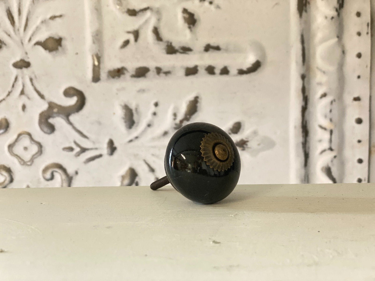 A black round knob with a geometric pattern in the background.