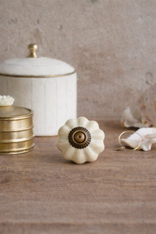Decorative white knob with gold center on a wooden surface with a neutral background