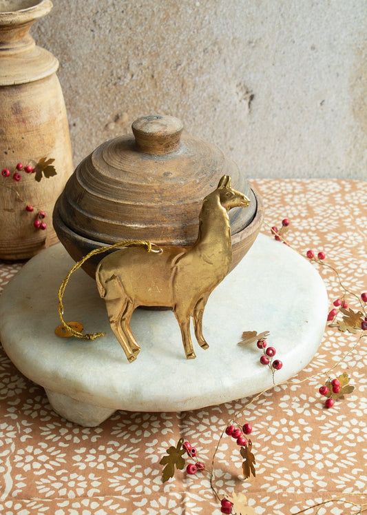 Brass llama ornament with gold string on marble tray and rustic background