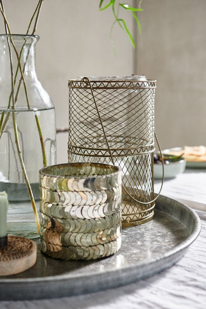 Decorative items including a wire mesh container and glass vase on a tray.