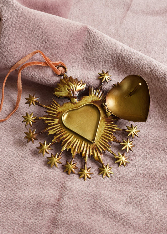 Decorative gold heart ornament with stars on a pink fabric background