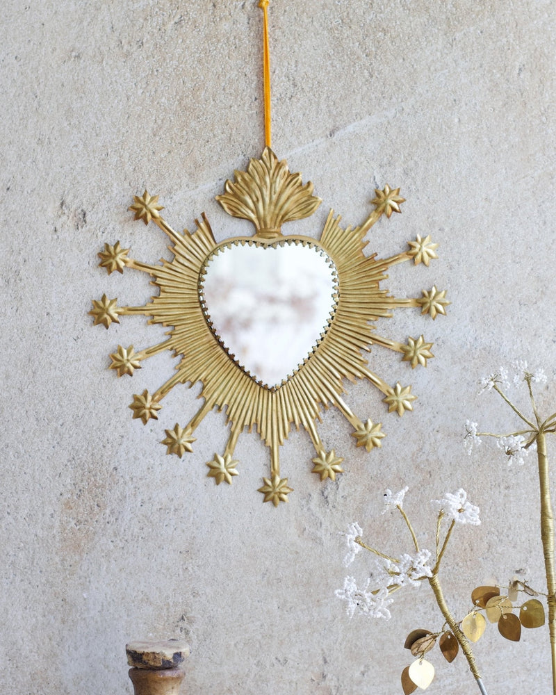 Decorative gold mirror with heart shape on a textured wall