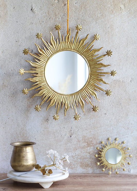 Decorative sunburst mirror with smaller mirror on a wooden surface and neutral wall background
