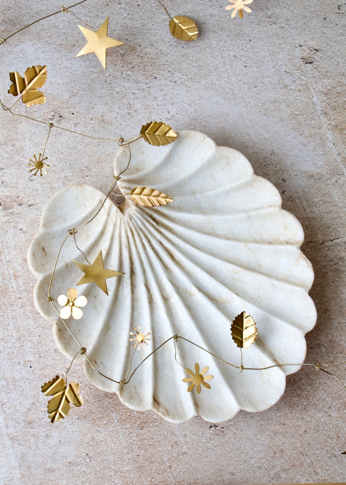 Decorative shell with gold stars and leaves on a textured surface