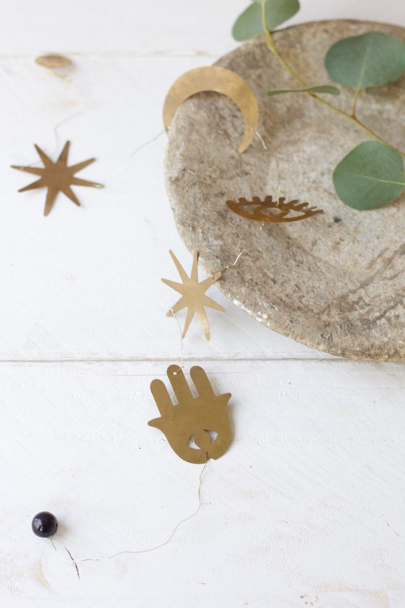 Decorative items including a stone tray with gold accents and eucalyptus leaves on a white surface.